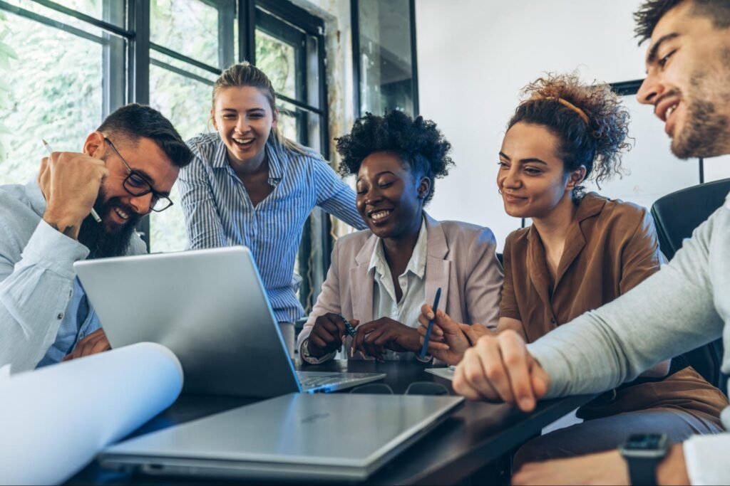 A diverse web design team brainstorming and working on a laptop in a modern office, representing professional author website development