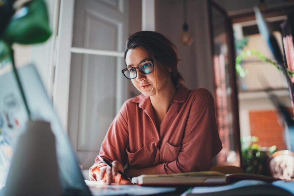 A focused author working on a laptop in a bright home office, planning her professional author website.